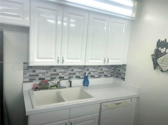 kitchen featuring sink, white cabinets, white dishwasher, and decorative backsplash