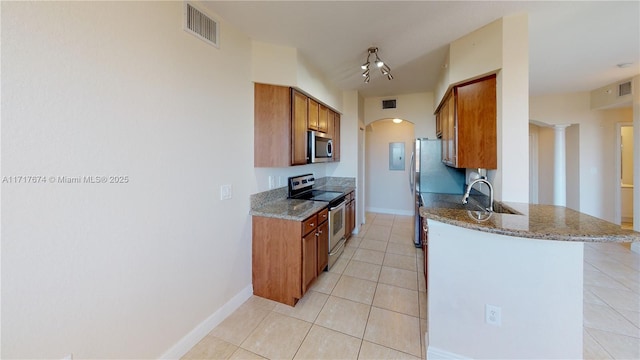 kitchen featuring sink, light tile patterned flooring, appliances with stainless steel finishes, light stone counters, and ornate columns