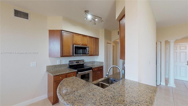 kitchen featuring light stone counters, sink, stainless steel appliances, and ornate columns