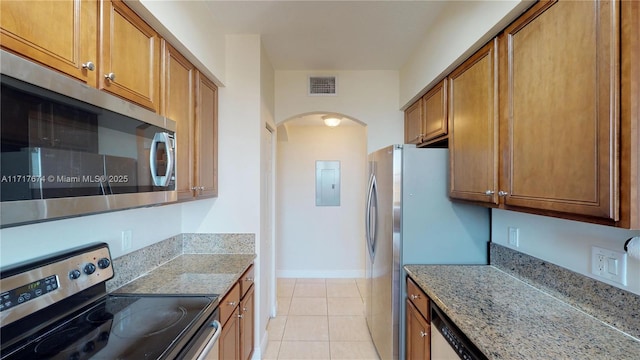 kitchen featuring light stone countertops, light tile patterned flooring, stainless steel appliances, and electric panel