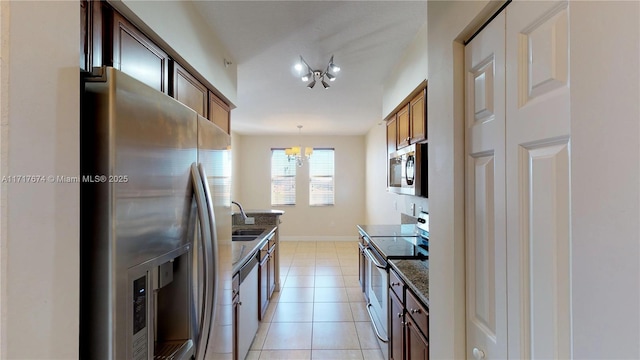 kitchen featuring an inviting chandelier, light tile patterned floors, appliances with stainless steel finishes, decorative light fixtures, and sink