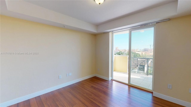 unfurnished room with dark wood-type flooring and a tray ceiling