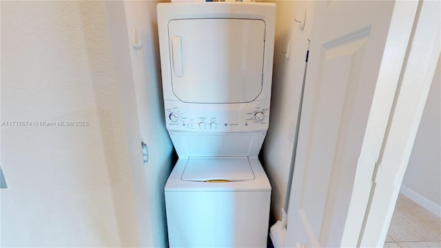 laundry area featuring stacked washer / dryer and light tile patterned flooring