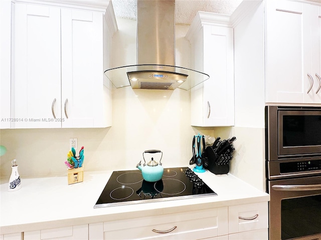 kitchen with appliances with stainless steel finishes, island exhaust hood, and white cabinetry