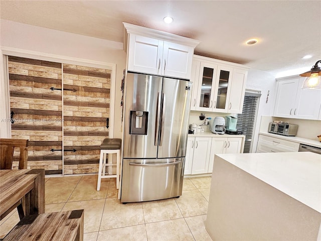 kitchen with stainless steel fridge with ice dispenser, light tile patterned floors, and white cabinetry