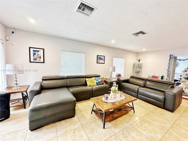 living room featuring a textured ceiling, light tile patterned flooring, and a healthy amount of sunlight