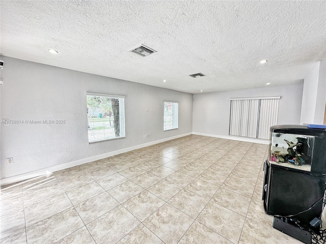 tiled empty room with a textured ceiling