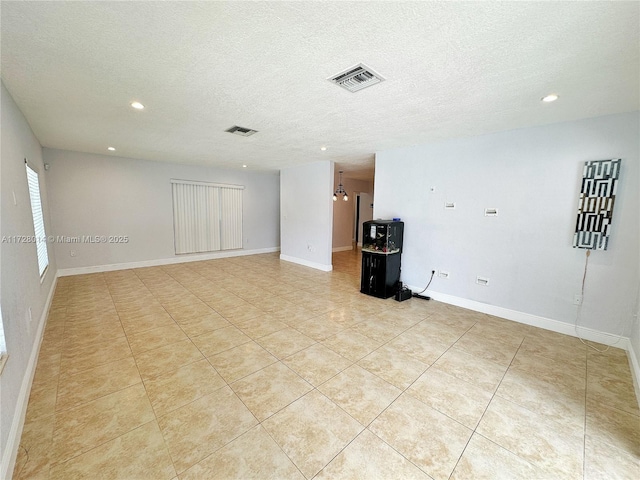 spare room with a textured ceiling and light tile patterned floors