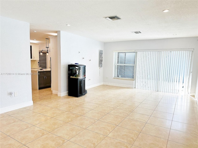 spare room with light tile patterned flooring and a textured ceiling