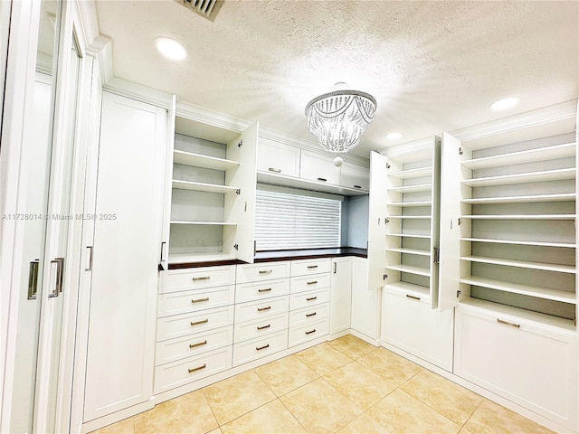 kitchen with white cabinetry, a textured ceiling, light tile patterned floors, and an inviting chandelier