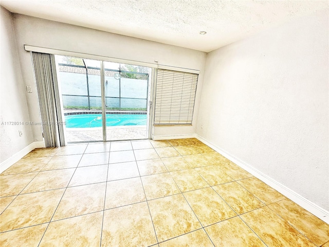 empty room featuring a textured ceiling and light tile patterned flooring