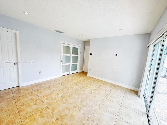 empty room featuring a textured ceiling and light tile patterned flooring