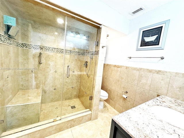 bathroom featuring toilet, vanity, tile walls, tile patterned floors, and an enclosed shower