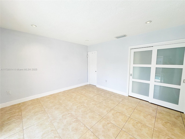 spare room featuring light tile patterned floors and a textured ceiling