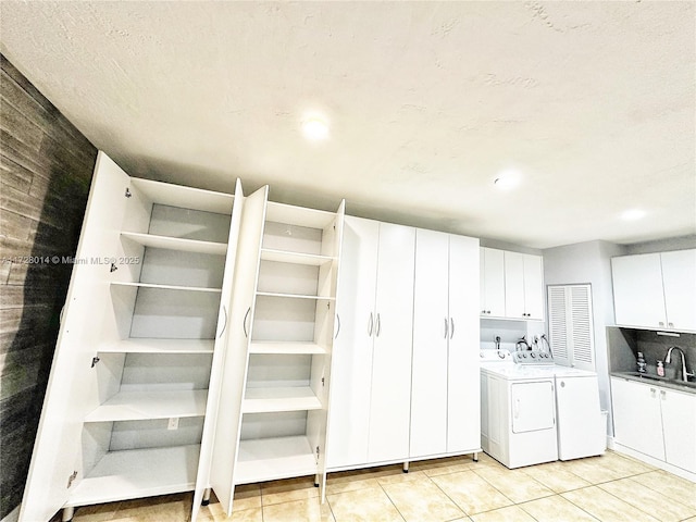 laundry area featuring cabinets, light tile patterned floors, sink, and independent washer and dryer