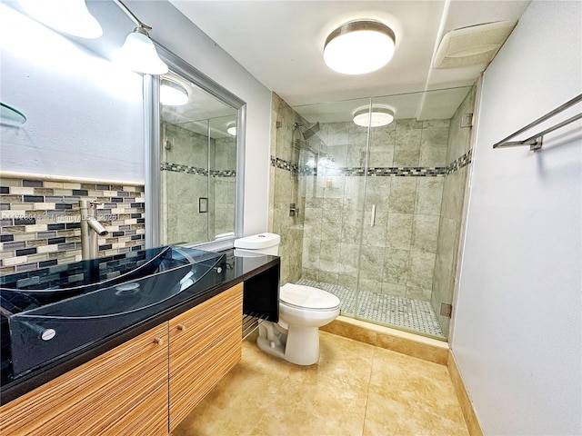 bathroom with toilet, vanity, tile patterned flooring, backsplash, and a shower with door