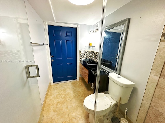 bathroom featuring toilet, vanity, tile patterned flooring, decorative backsplash, and an enclosed shower