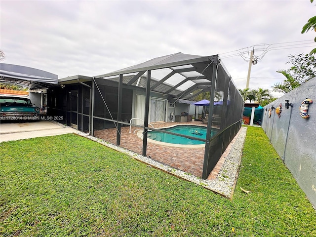 view of pool featuring glass enclosure, a yard, and a patio