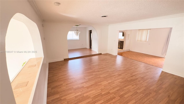 spare room with hardwood / wood-style flooring, a textured ceiling, and crown molding