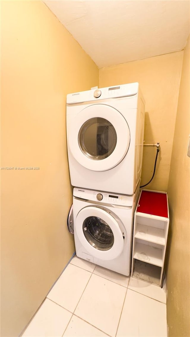 laundry area with stacked washing maching and dryer and tile patterned flooring