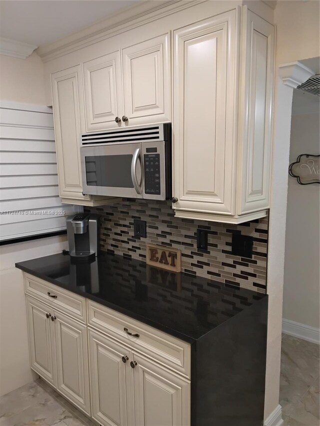 kitchen with black refrigerator, white cabinetry, and ornamental molding