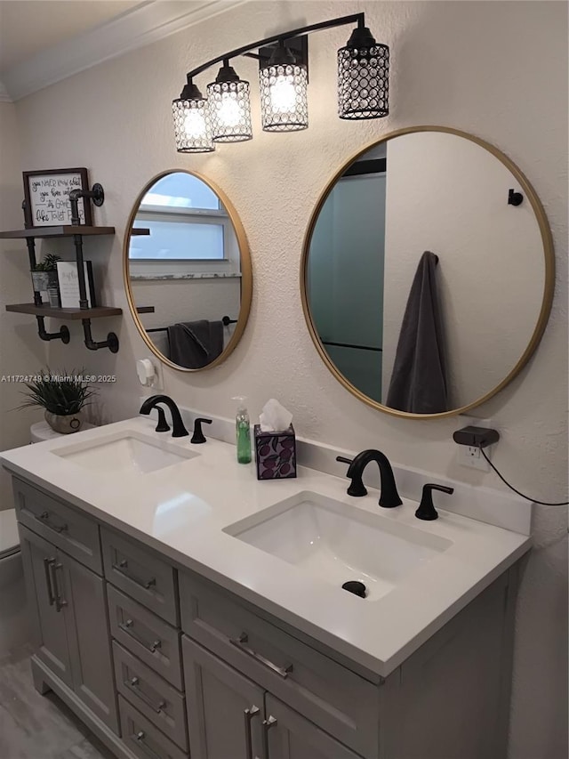 bathroom featuring double vanity, ornamental molding, a sink, and toilet