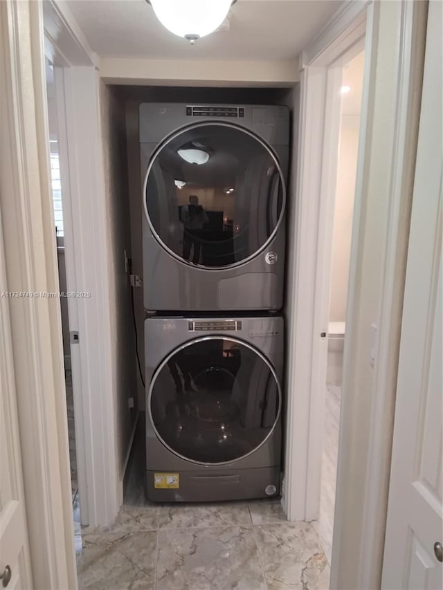 clothes washing area featuring stacked washer and dryer, laundry area, and marble finish floor