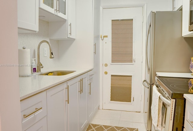 kitchen featuring light tile patterned flooring, stainless steel electric range, white cabinets, light stone counters, and sink