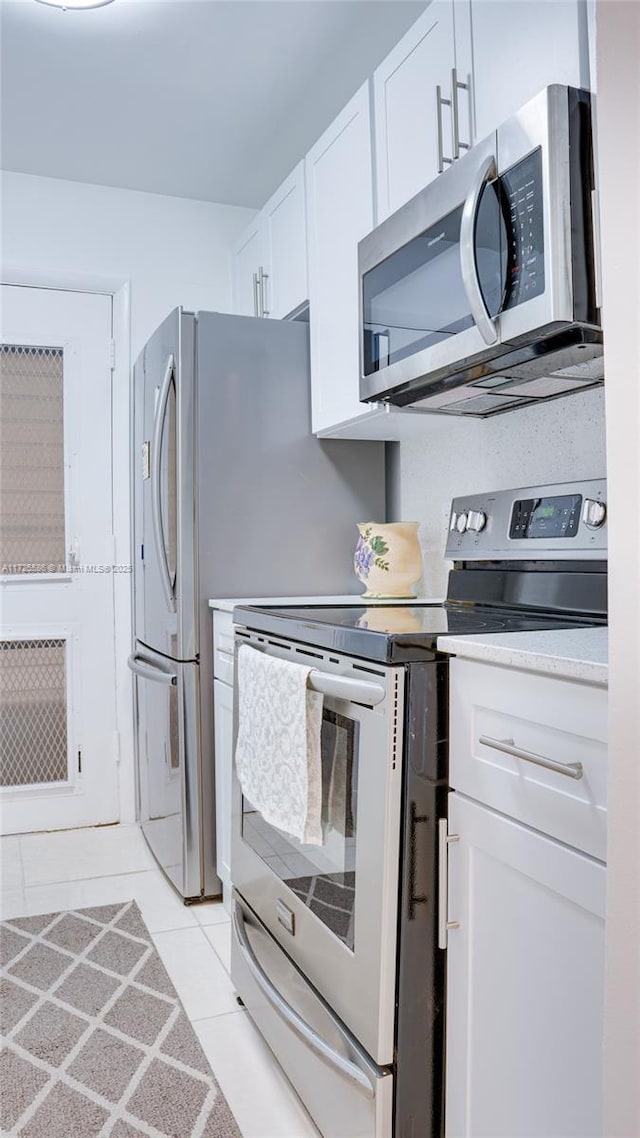 kitchen with light tile patterned floors, stainless steel appliances, and white cabinetry