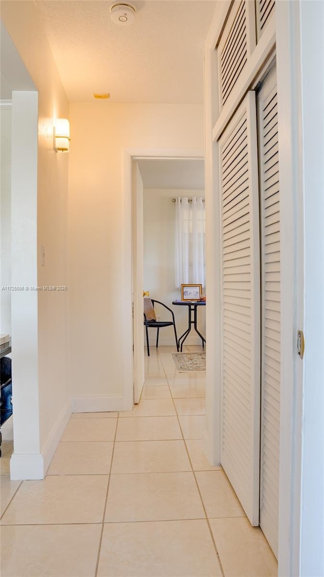 corridor featuring a textured ceiling and light tile patterned floors