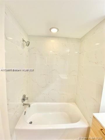 bathroom featuring tiled shower / bath combo and vanity