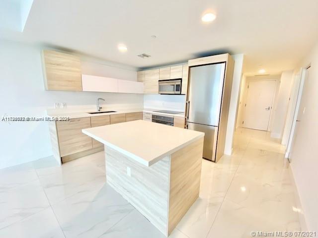 kitchen featuring sink, white cabinets, stainless steel appliances, and a kitchen island