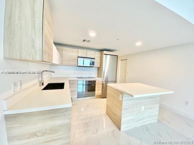 kitchen featuring black appliances, light brown cabinetry, sink, and a center island