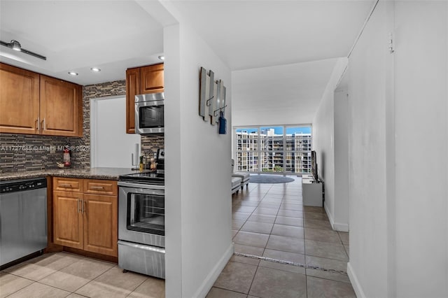 kitchen with tasteful backsplash, stainless steel appliances, expansive windows, and light tile patterned flooring