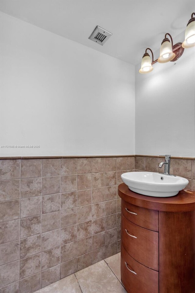 bathroom featuring tile patterned flooring, vanity, and tile walls