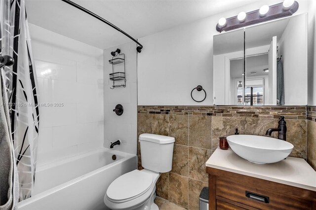 full bathroom with shower / bath combo with shower curtain, vanity, toilet, and tile walls