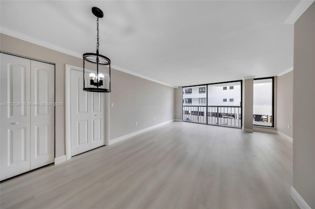 unfurnished living room featuring ornamental molding, a chandelier, light hardwood / wood-style flooring, and expansive windows