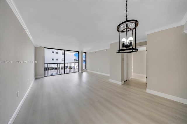 unfurnished living room with light wood-type flooring, ornamental molding, floor to ceiling windows, and a notable chandelier