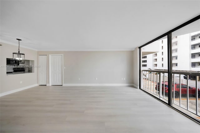 unfurnished living room with floor to ceiling windows, a wealth of natural light, a chandelier, and ornamental molding