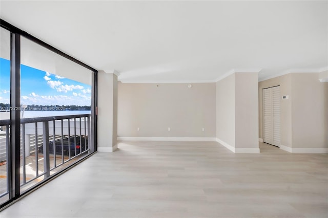 spare room featuring a water view, a wall of windows, and crown molding