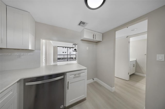 kitchen featuring backsplash, white cabinetry, stainless steel dishwasher, and light hardwood / wood-style flooring