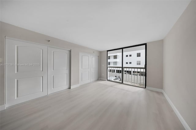 unfurnished bedroom featuring light wood-type flooring, expansive windows, and access to exterior