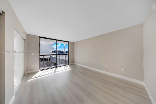 spare room with light hardwood / wood-style floors and expansive windows