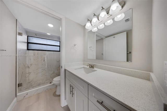 bathroom featuring toilet, vanity, a shower with door, and hardwood / wood-style floors