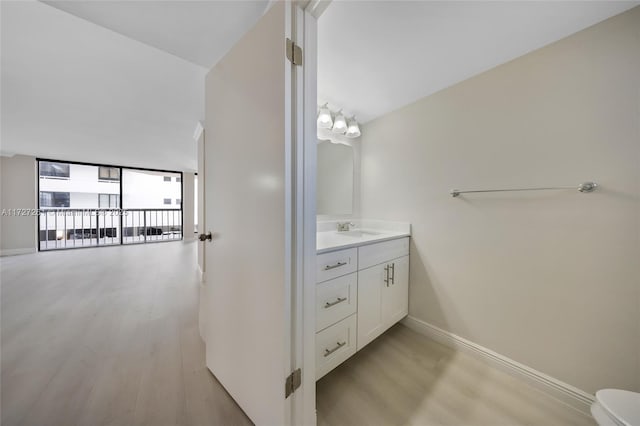 bathroom featuring wood-type flooring, vanity, toilet, a notable chandelier, and expansive windows