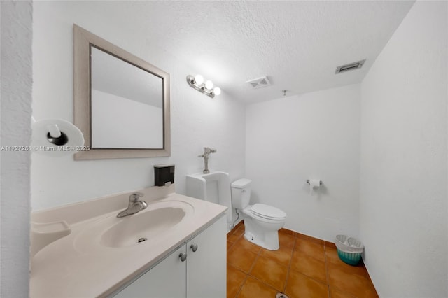 bathroom with a textured ceiling, toilet, tile patterned flooring, and vanity