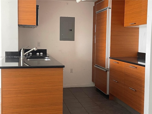 kitchen featuring dark tile patterned flooring, sink, paneled built in refrigerator, and electric panel