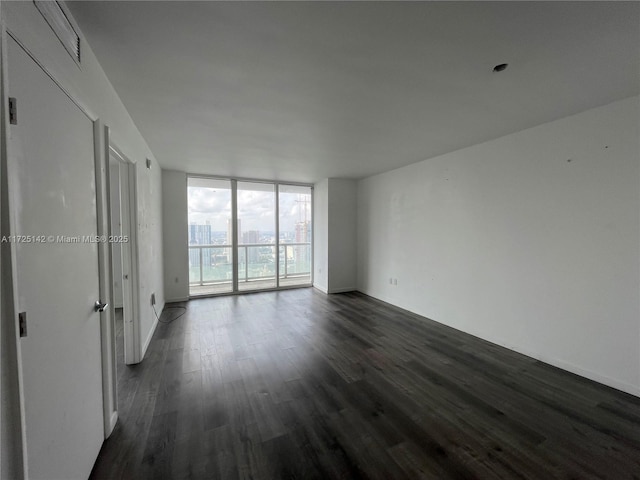 empty room featuring dark hardwood / wood-style floors and expansive windows