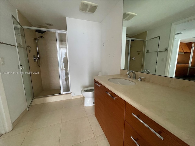 bathroom with toilet, vanity, a shower with door, and tile patterned floors