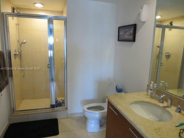 bathroom featuring toilet, tile patterned flooring, a shower with shower door, and vanity